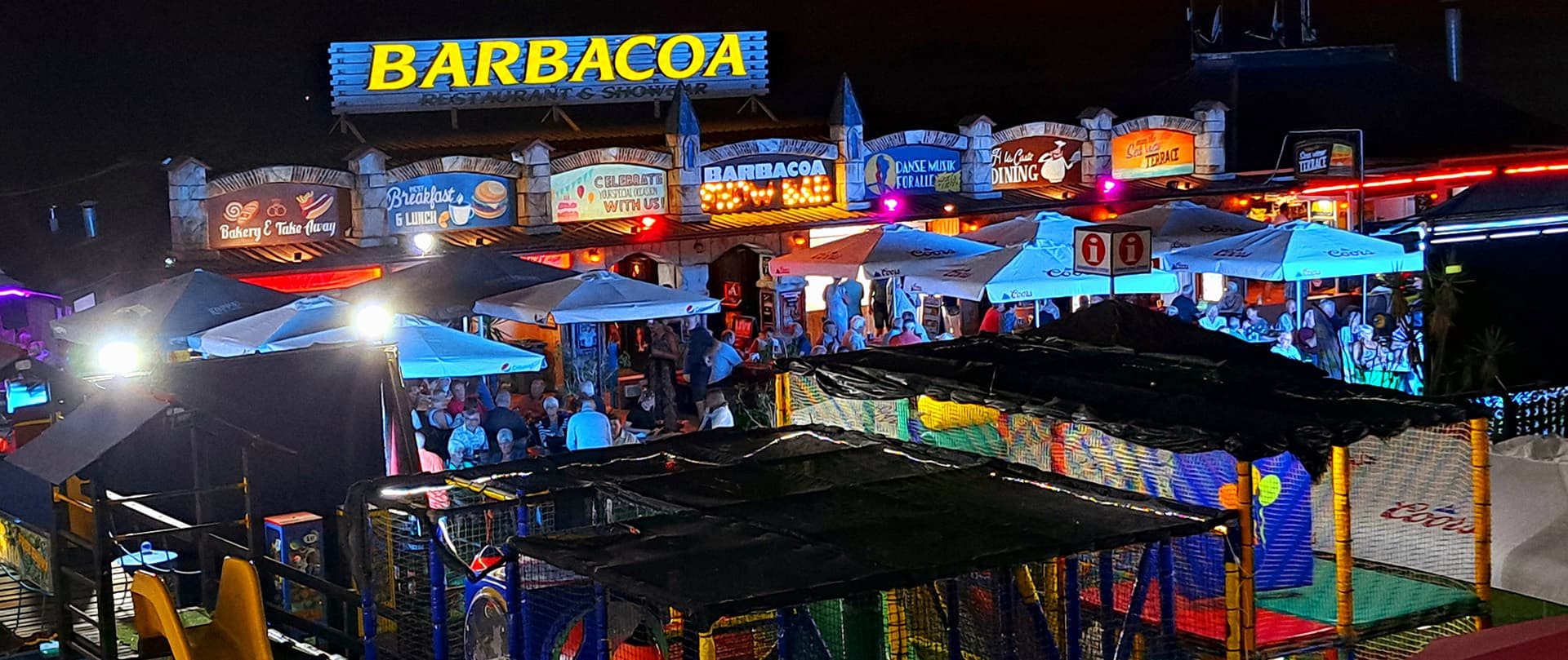 Barbacoa Restaurant & Showbar lit up at night in El Puerto de Santa María, Cádiz, busy terrace and family play area